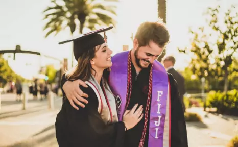 Female graduate walking in the arms of a guy.