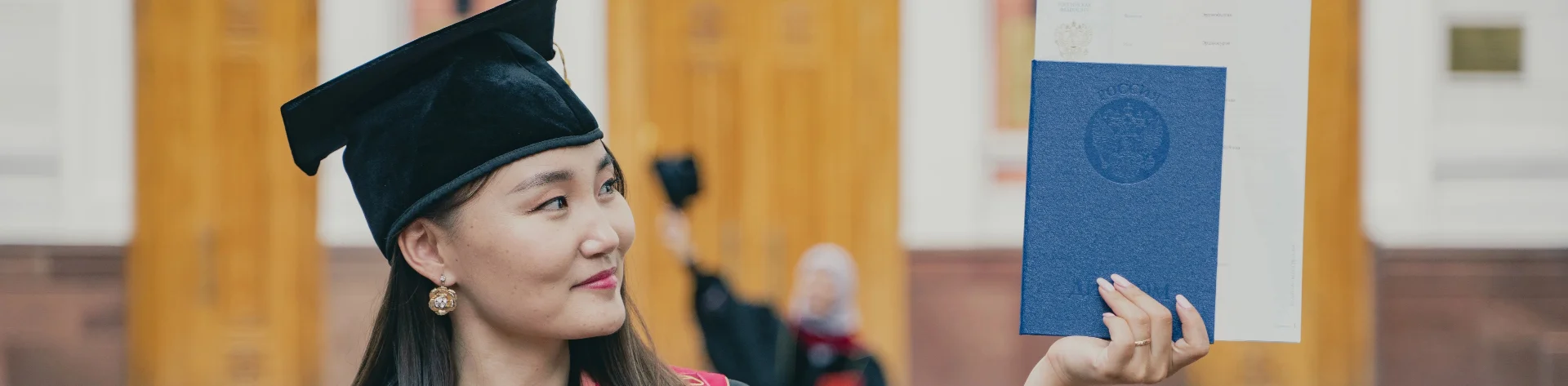 Ein asiatisches Mädchen zeigt ihr blaues Zeugnis bei der Abschlussfeier