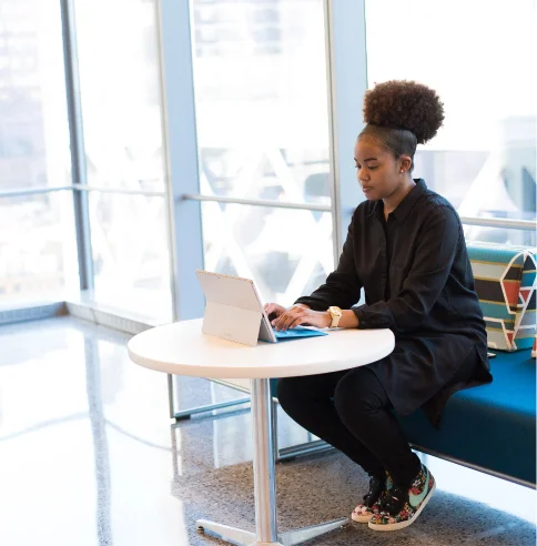 Black woman focuses on her laptop as she works.