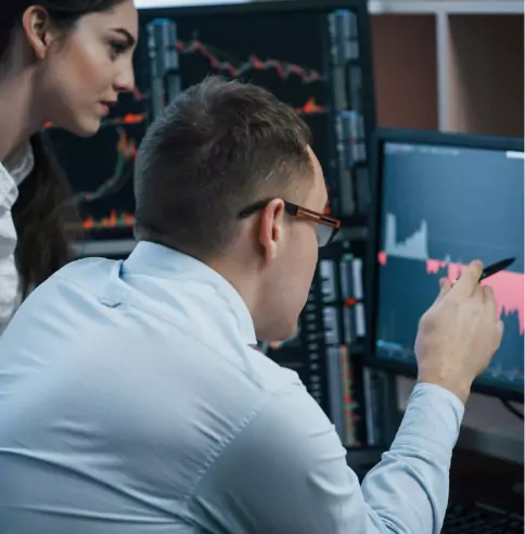 A woman and a man in front of several screens.